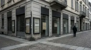 Vetrine di negozi vuoti con cartelli 'affittasi' e 'vendesi' in una strada deserta