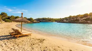 Spiaggia tranquilla con due lettini sotto un ombrellone di paglia e mare turchese